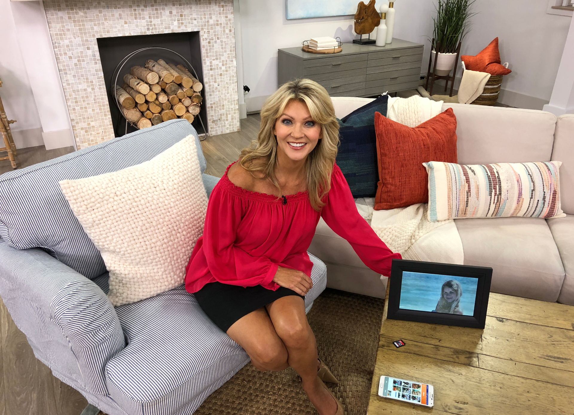 Woman in red blouse sitting on a couch with a laptop.